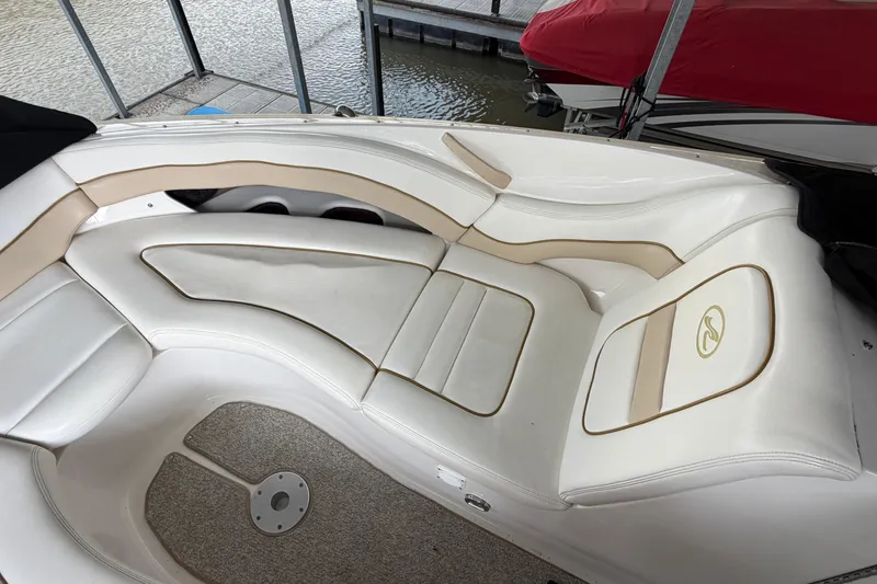 Slide: The Image of 2003 Sea Ray 290 Bowrider interior with white and beige seating, docked by water. - 21