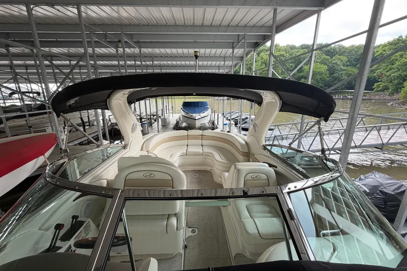 Slide: The Image of 2003 Sea Ray 290 Bowrider docked under a covered marina with lush greenery. - 25