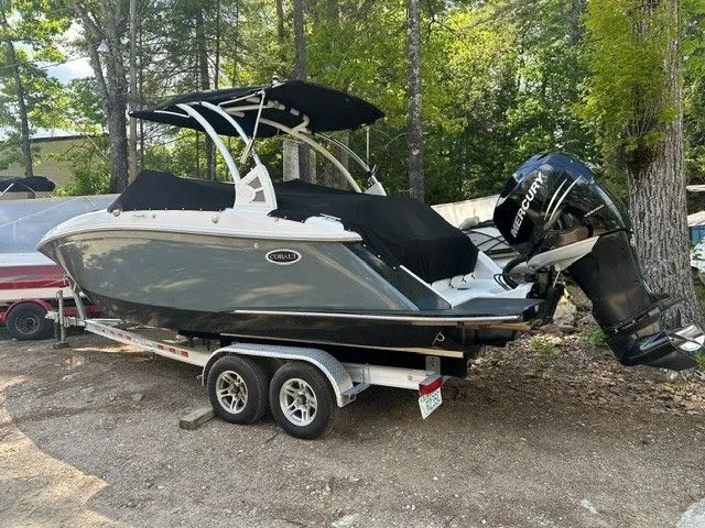 Slide: The Image of 2018 Cobalt 23 SC boat on trailer parked in wooded area. - 2