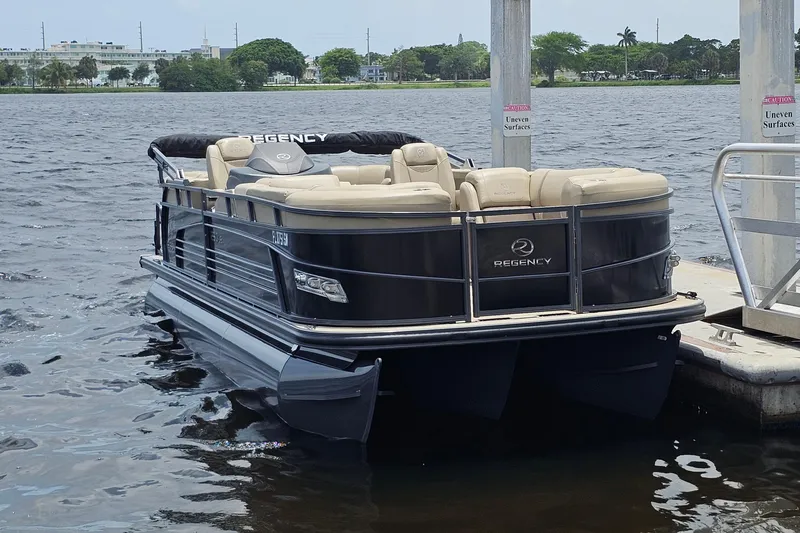 Slide: The Image of 2020 Regency 230 LE3 pontoon boat docked on a calm lake. - 17