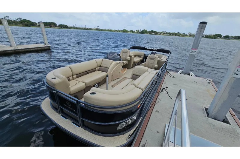 Slide: The Image of 2020 Regency 230 LE3 pontoon boat docked on a calm lake. - 19