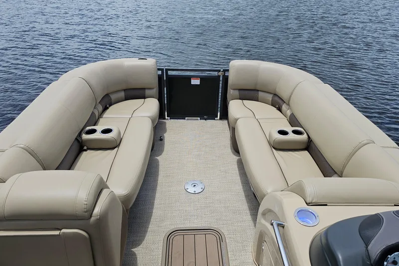 Slide: The Image of 2020 Regency 230 LE3 pontoon boat interior with beige seating on water. - 34