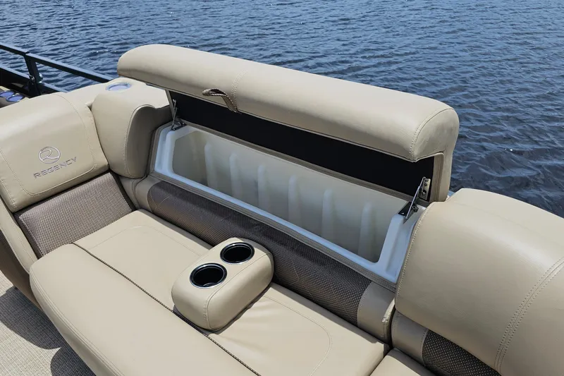 Slide: The Image of 2020 Regency 230 LE3 boat seat with storage compartment and cup holders by the water. - 38