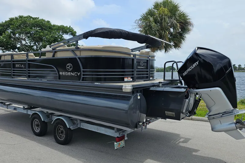 Slide: The Image of 2020 Regency 230 LE3 pontoon boat on trailer by a lake. - 4
