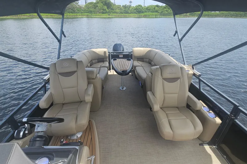 Slide: The Image of 2020 Regency 230 LE3 pontoon boat interior with luxurious seating on a calm lake. - 44