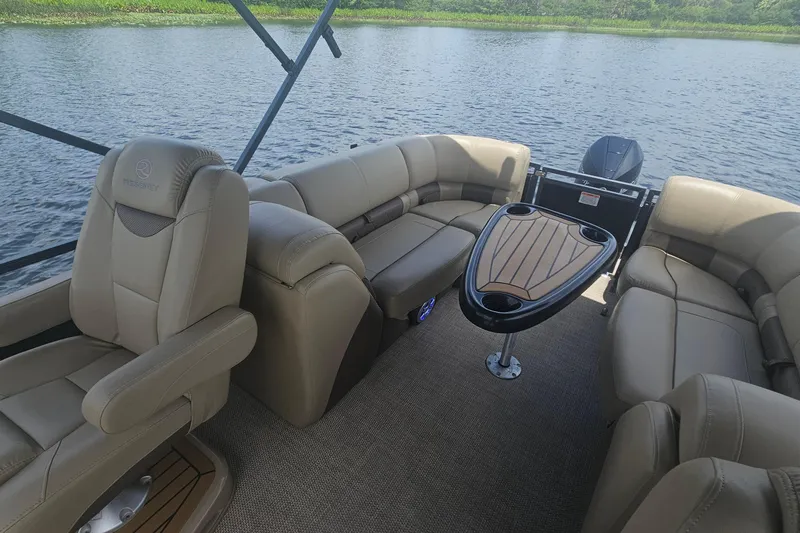 Slide: The Image of Luxurious 2020 Regency 230 LE3 pontoon boat interior with plush seating and table on a serene lake. - 46