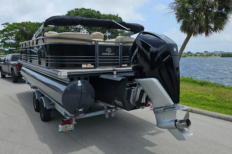 Slide: The Image of 2020 Regency 230 LE3 pontoon boat on trailer by a lakeside road. - 5