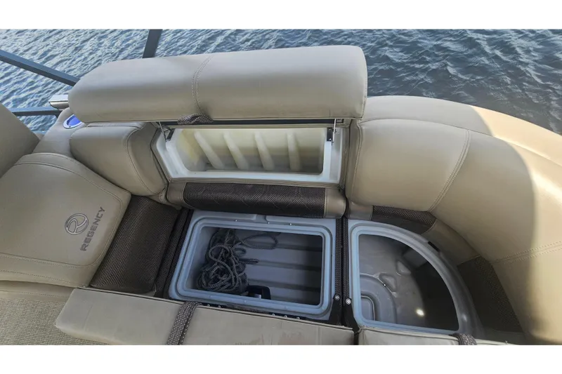 Slide: The Image of 2020 Regency 230 LE3 boat seating with storage compartments open, showing ropes and cooler. - 50