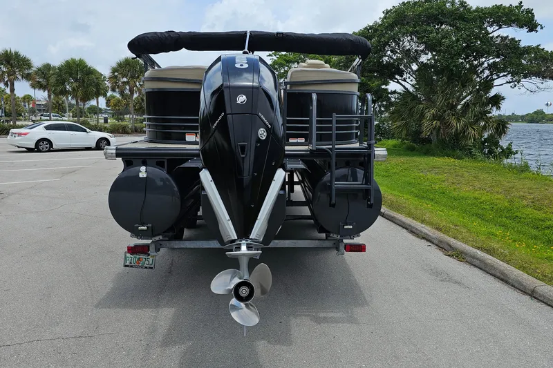 Slide: The Image of 2020 Regency 230 LE3 pontoon boat on trailer near waterfront and palm trees. - 6