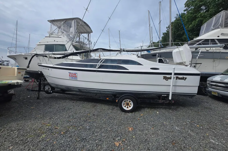 The Image of 2005 MacGregor 26 sailboat for sale on trailer in marina. - 0