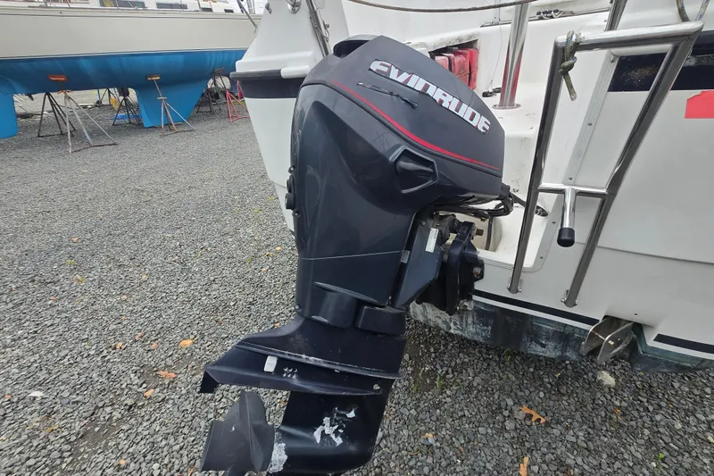Slide: The Image of Evinrude outboard motor on a 2005 MacGregor 26 sailboat, parked on gravel. - 2