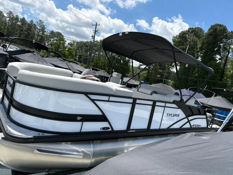 Slide: The Image of 2026 Sylvan X-3 DLZ BAR pontoon boat parked outdoors. - 3