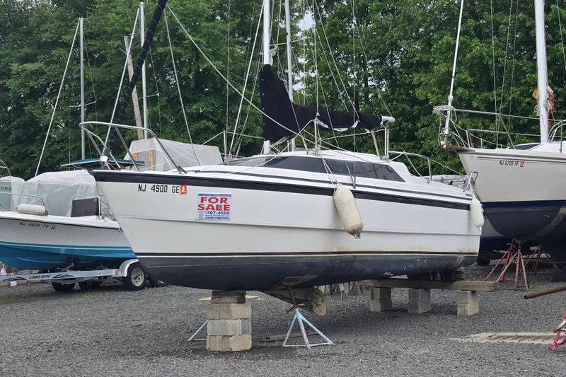 Slide: The Image of 1997 MacGregor 26X sailboat for sale, displayed on stands in a boatyard. - 3