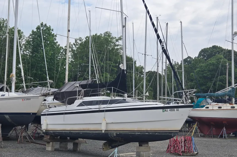 Slide: The Image of 1997 MacGregor 26X sailboat on dry dock, surrounded by other boats and trees. - 4