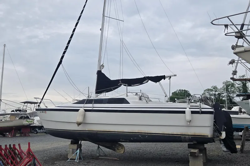 Slide: The Image of 1997 MacGregor 26X sailboat on dry dock, with mast and black sail cover. - 5