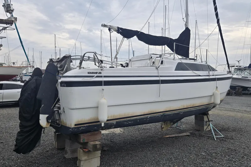 Slide: The Image of 1997 MacGregor 26X sailboat on dry dock, with visible hull and rigging. - 6