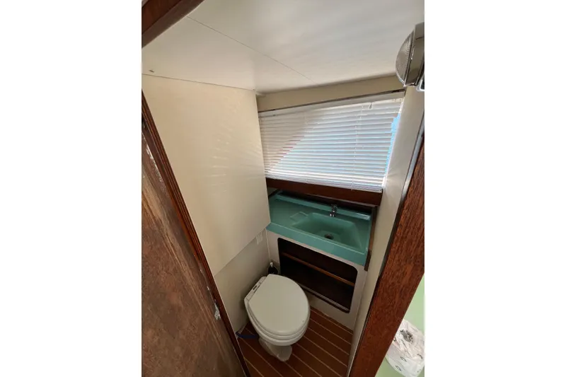 Slide: The Image of 1966 Chris-Craft 27 Commander bathroom with toilet, sink, and window blinds. - 42