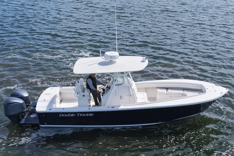 Slide: The Image of 2019 Regulator 28 Forward Seating boat cruising on water, featuring dual engines. - 15