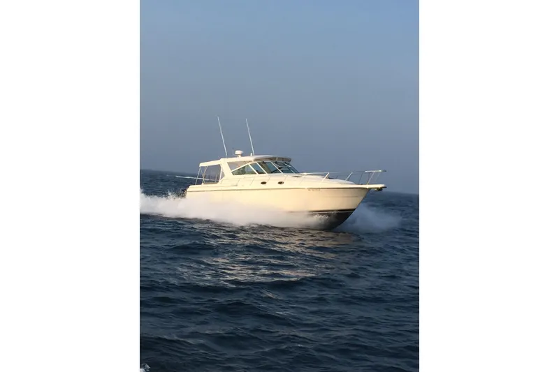 The Image of 1995 Tiara Yachts 4000 Express cruising on open water under clear skies. - 1