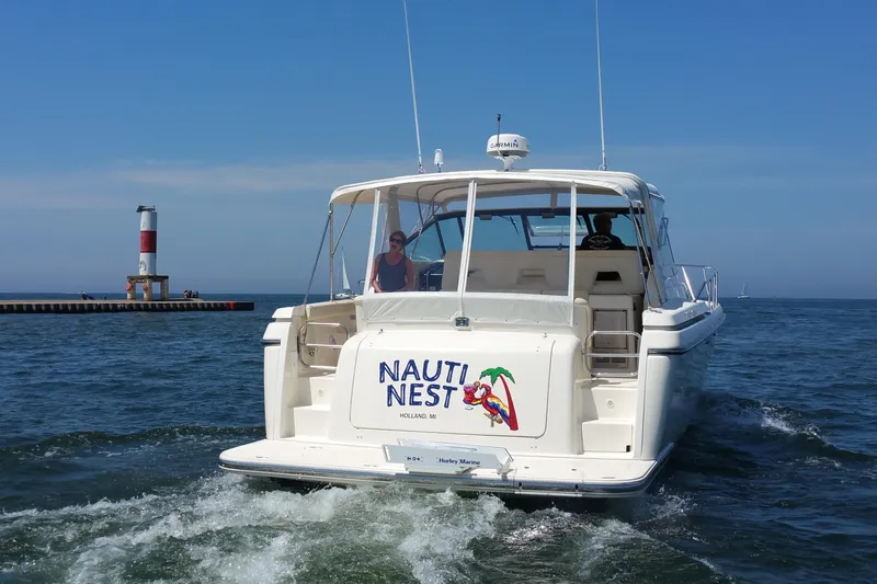 Slide: The Image of 1995 Tiara Yachts 4000 Express boat named "Nauti Nest" cruising near a lighthouse. - 4