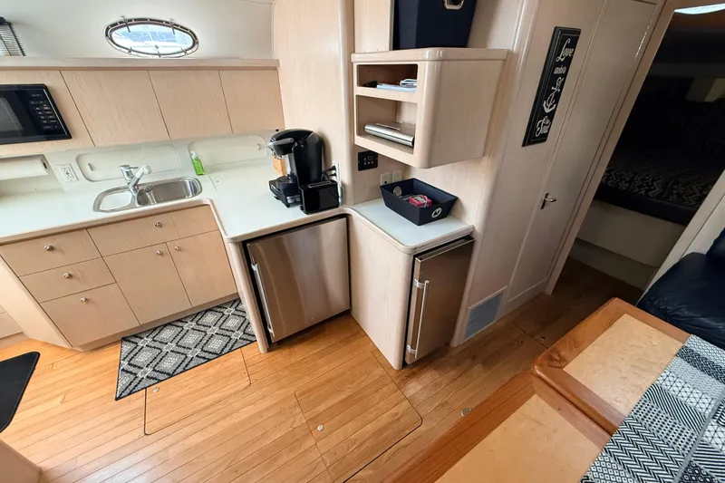 Slide: The Image of 1995 Tiara Yachts 4000 Express interior with kitchenette, featuring sink, fridge, and wooden cabinetry. - 43