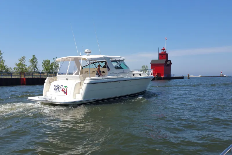 Slide: The Image of 1995 Tiara Yachts 4000 Express cruising near a red lighthouse on a sunny day. - 5