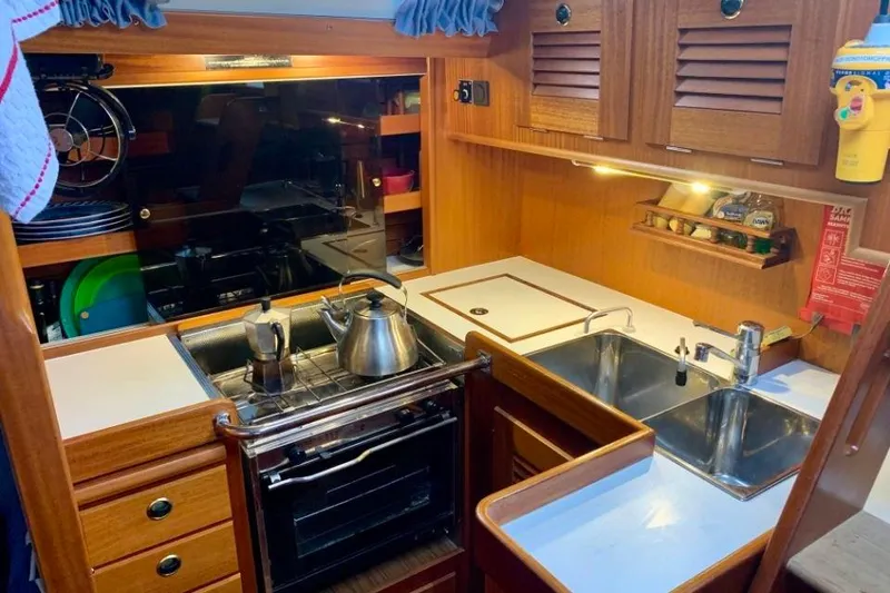 Slide: The Image of 1997 Hallberg-Rassy 39 yacht kitchen with stove, sink, and wooden cabinetry. - 18