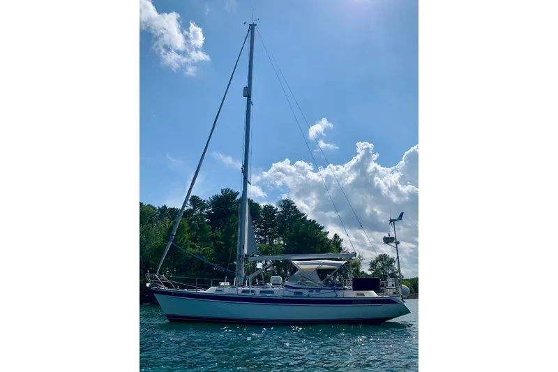 Slide: The Image of 1997 Hallberg-Rassy 39 sailboat on water, clear sky, and trees in background. - 2
