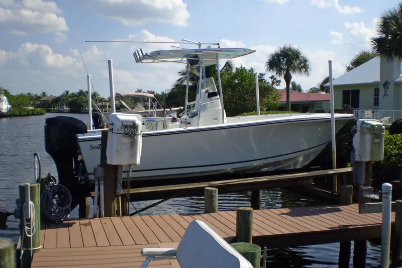 Slide: The Image of 2001 Sea Craft Master Angler 21 boat docked by a scenic waterfront with palm trees. - 2