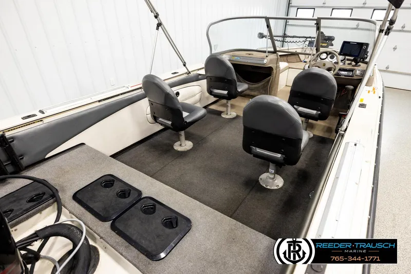 Slide: The Image of 2004 Crestliner 2050 Sportfish boat interior with seating and dashboard in a garage setting. - 11