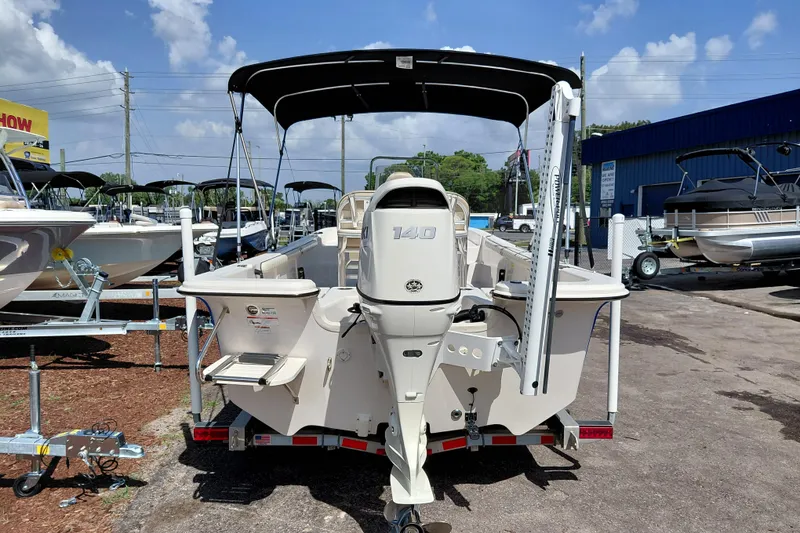 Slide: The Image of 2021 Carolina Skiff 21 LS boat with outboard motor, parked at a dealership under a sunny sky. - 6