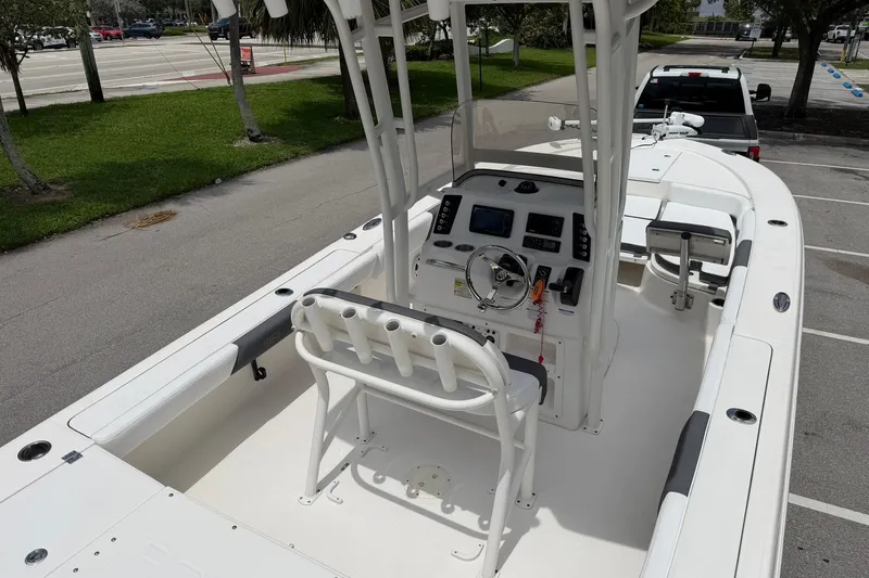 Slide: The Image of 2015 Robalo 246 Cayman boat interior with helm, seating, and console in a parking lot. - 11