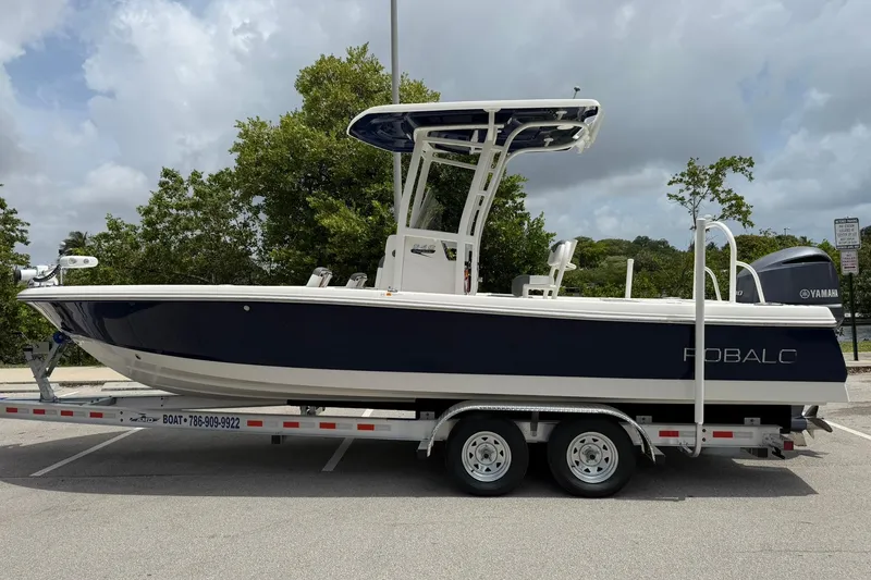 Slide: The Image of 2015 Robalo 246 Cayman boat on trailer, parked outdoors with trees in background. - 6