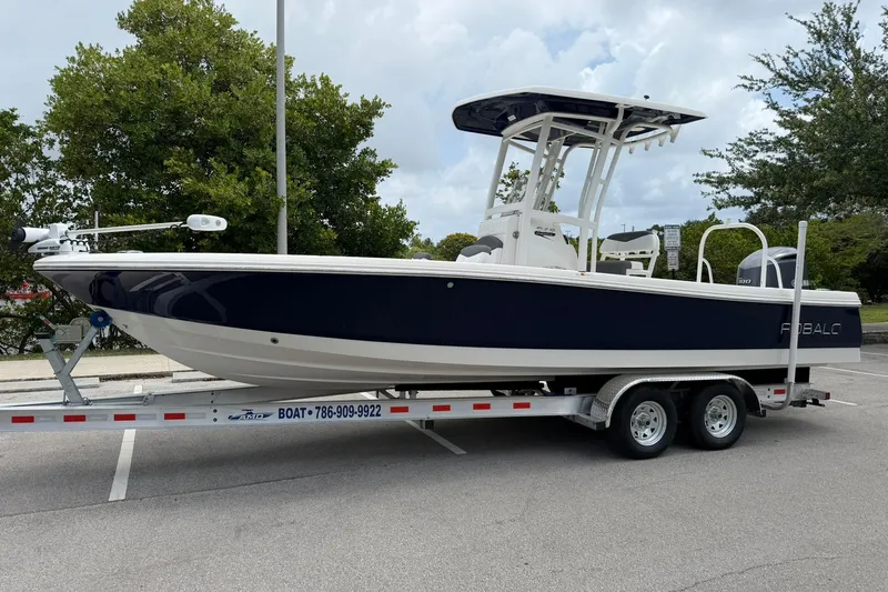 Slide: The Image of 2015 Robalo 246 Cayman boat on trailer, parked in a lot with trees in the background. - 7