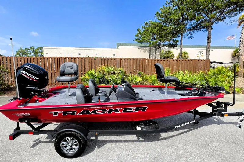 Slide: The Image of 2026 Tracker Pro Team 175 boat, red, parked outdoors, featuring Mercury engine and fishing seats. - 8
