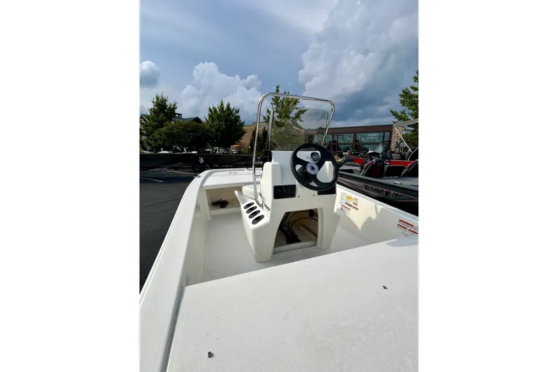 Slide: The Image of 2026 Mako Pro Skiff 13 CC boat with steering console, parked outdoors under cloudy sky. - 4