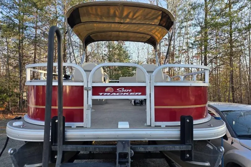 Slide: The Image of 2026 Sun Tracker Bass Buggy 16 XL Select pontoon boat in wooded area. - 2