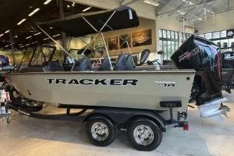 The Image of 2026 Tracker Targa V-18 Combo boat displayed indoors with trailer and outboard motor. - 0