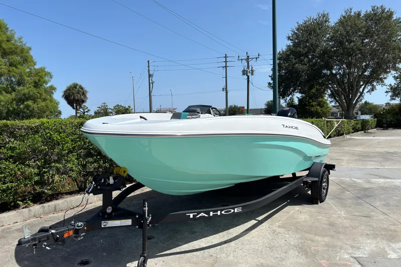 Slide: The Image of 2026 Tahoe T18 boat on trailer, parked outdoors, showcasing sleek design and mint green hull. - 2