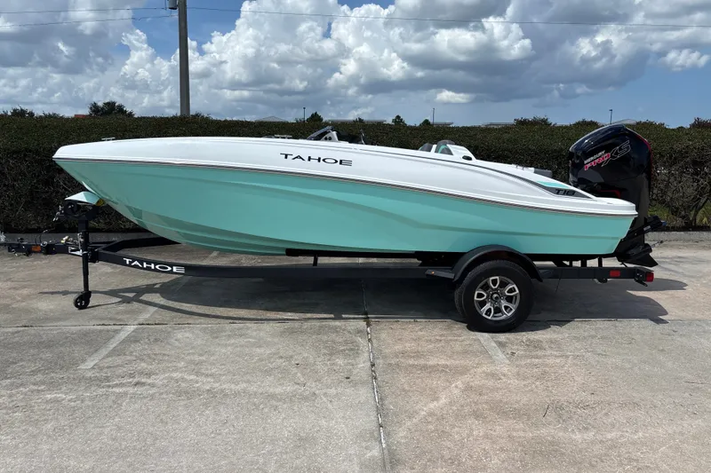 The Image of 2026 Tahoe T18 boat on trailer, mint green hull, parked outdoors under cloudy sky. - 0