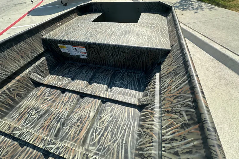 Slide: The Image of 2026 Tracker Grizzly 15 Jon boat with camouflage pattern on concrete surface. - 22