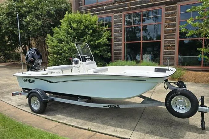 Slide: The Image of 2026 Mako Pro Skiff 15 CC boat on trailer, parked outdoors near a building. - 2