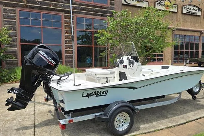 Slide: The Image of 2026 Mako Pro Skiff 15 CC boat on trailer, parked outdoors near a building. - 3