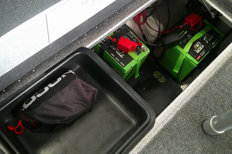 Slide: The Image of 2024 Nitro Z21 XL boat battery compartment with green batteries and storage tray. - 11