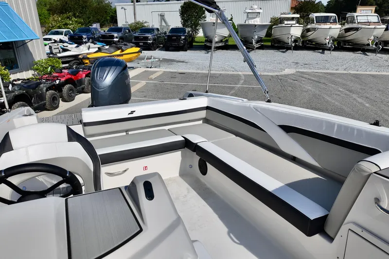Slide: The Image of 2026 Starcraft SVX 211 OB boat interior with seating and steering wheel, parked outdoors. - 9