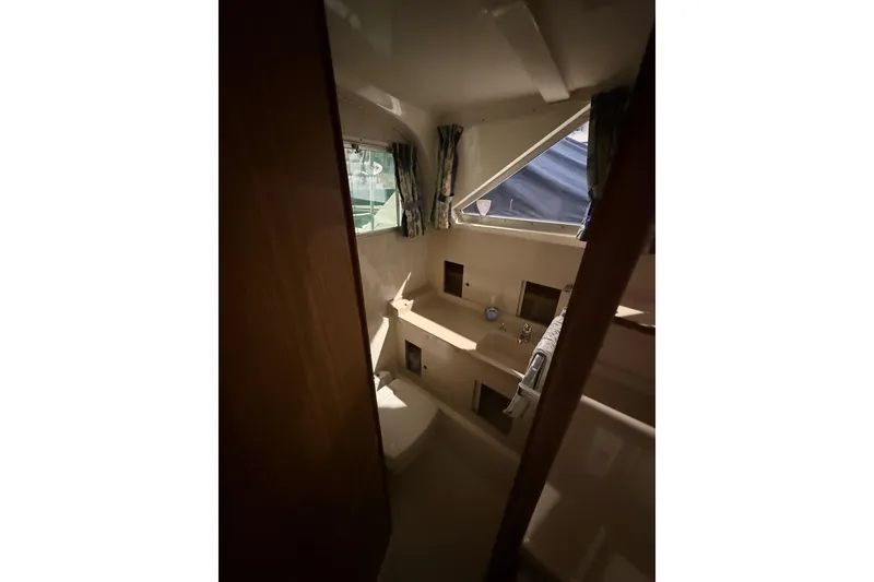 Slide: The Image of Interior of 1973 Bertram 28 Flybridge Cruiser, featuring compact bathroom with window and sink. - 11