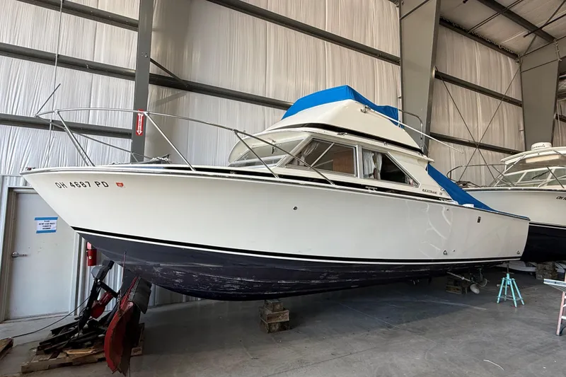 The Image of 1973 Bertram 28 Flybridge Cruiser in storage, showcasing classic design and blue accents. - 0