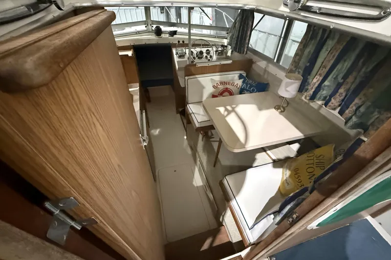 Slide: The Image of 1973 Bertram 28 Flybridge Cruiser interior with seating, table, and helm station. - 9