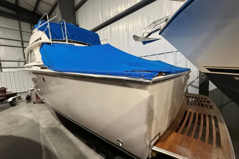Slide: The Image of 1973 Bertram 28 Flybridge Cruiser with blue cover in indoor storage. - 1