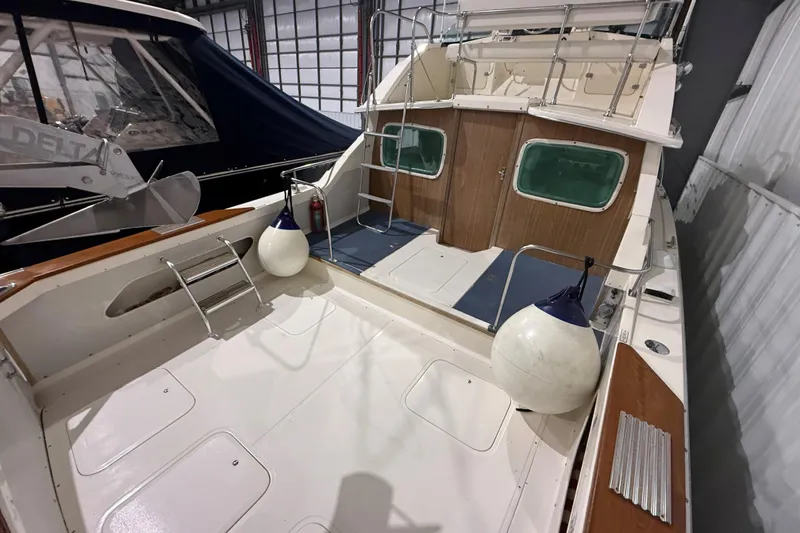 Slide: The Image of 1973 Bertram 28 Flybridge Cruiser in a marina, showcasing spacious deck and classic design. - 3